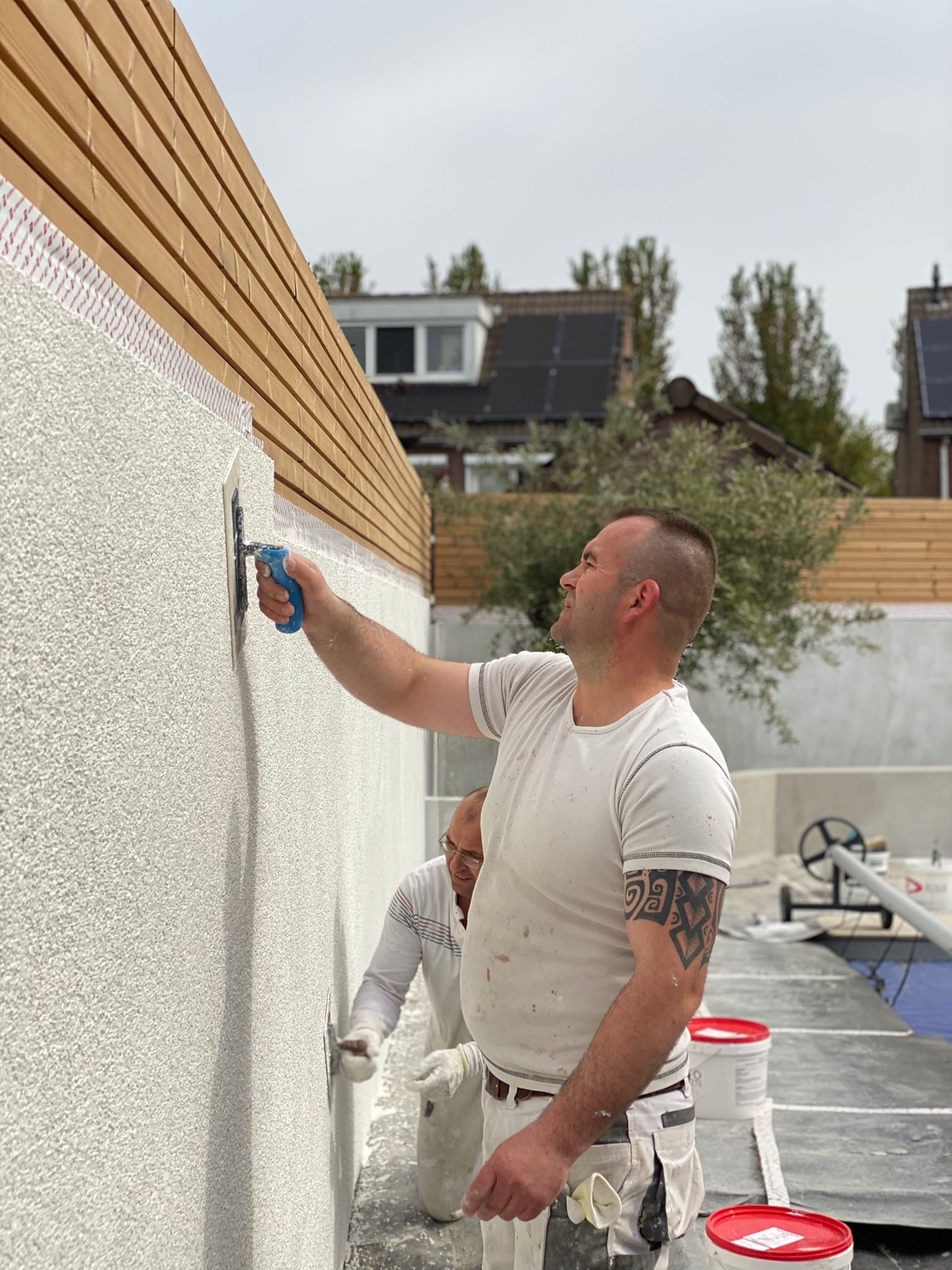 Demiri spackspuit een buitenmuur in de tuin van een klant