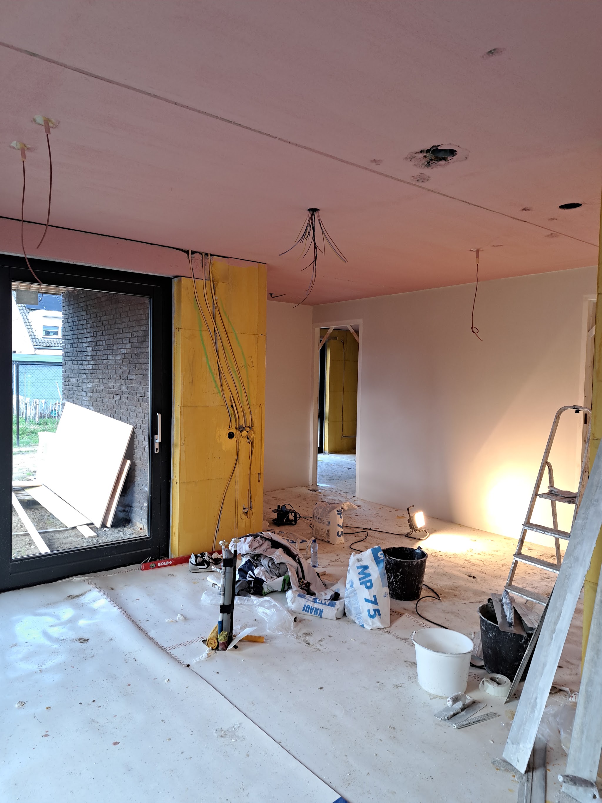 Woonkamer met voorbereide wanden tijdens het spuitwerk